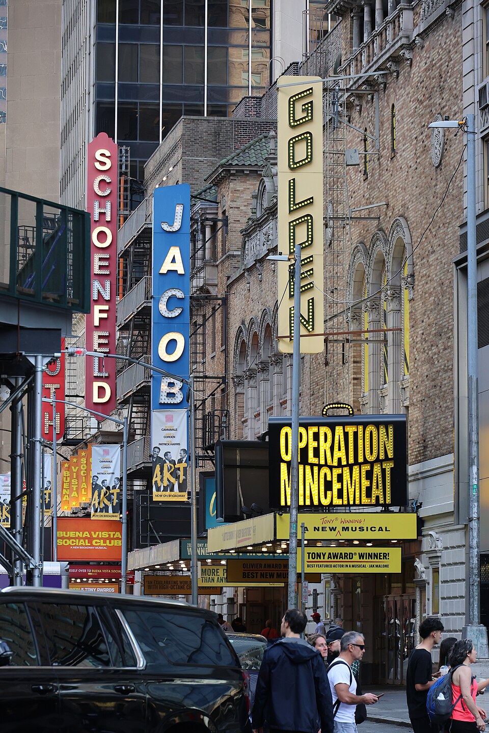 Off-Broadway and Broadway theater marquees along a busy Midtown Manhattan block