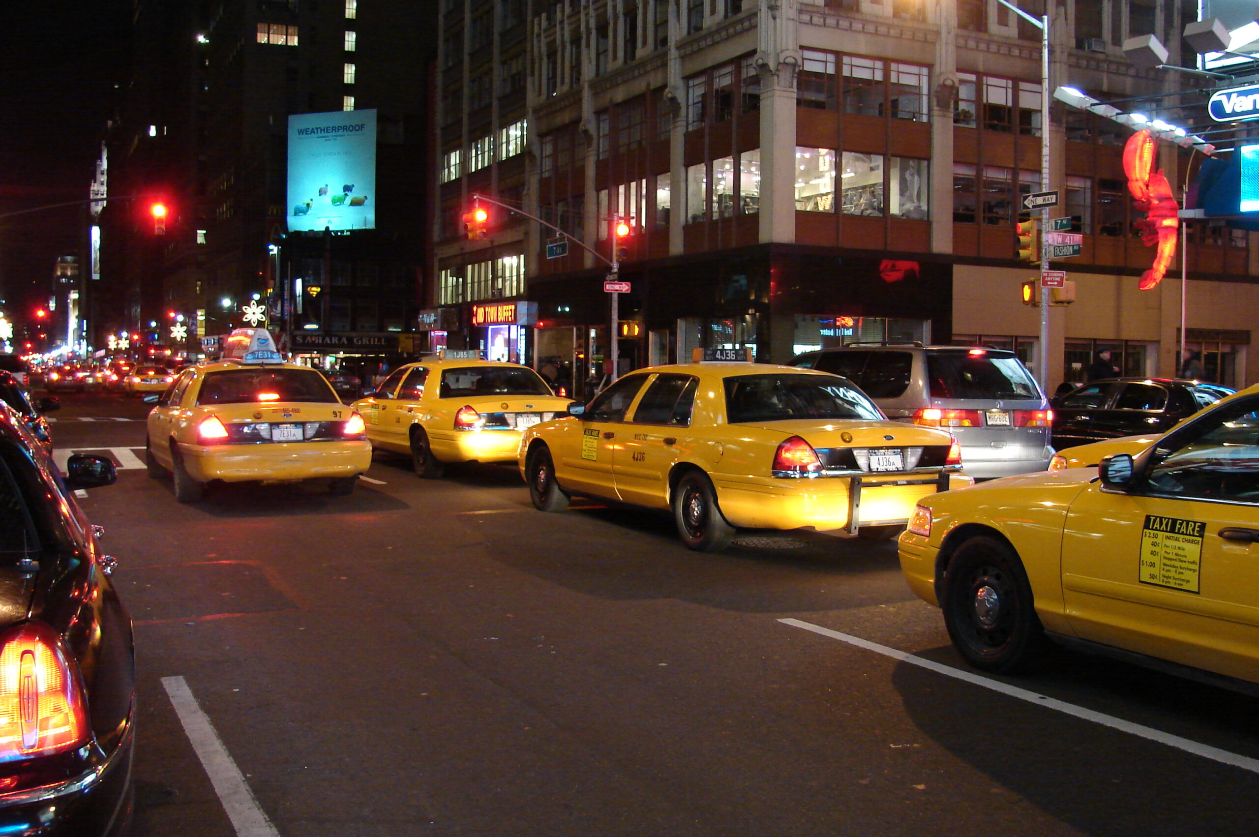 Yellow taxis in Midtown Manhattan at night for Uber vs subway NYC night-out planning