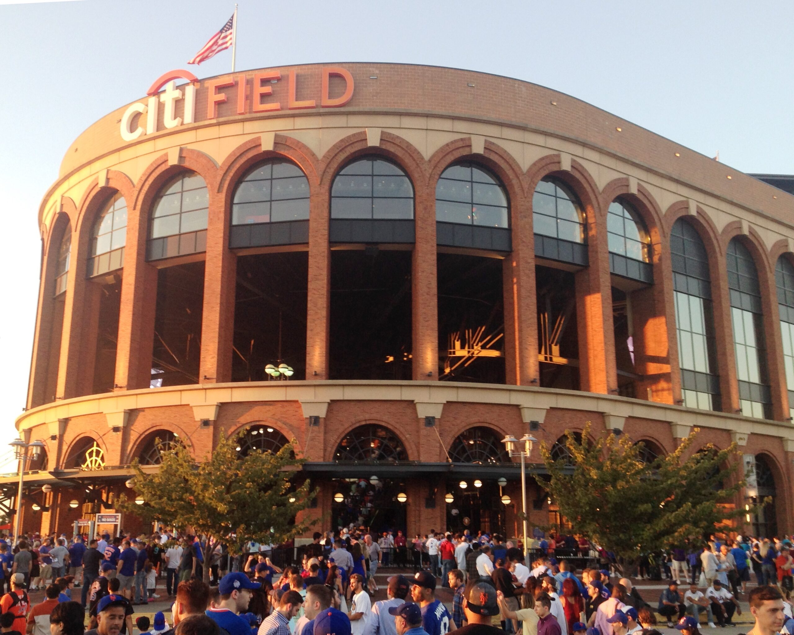 Fans seated at Citi Field before a New York baseball game with a large American flag on the field