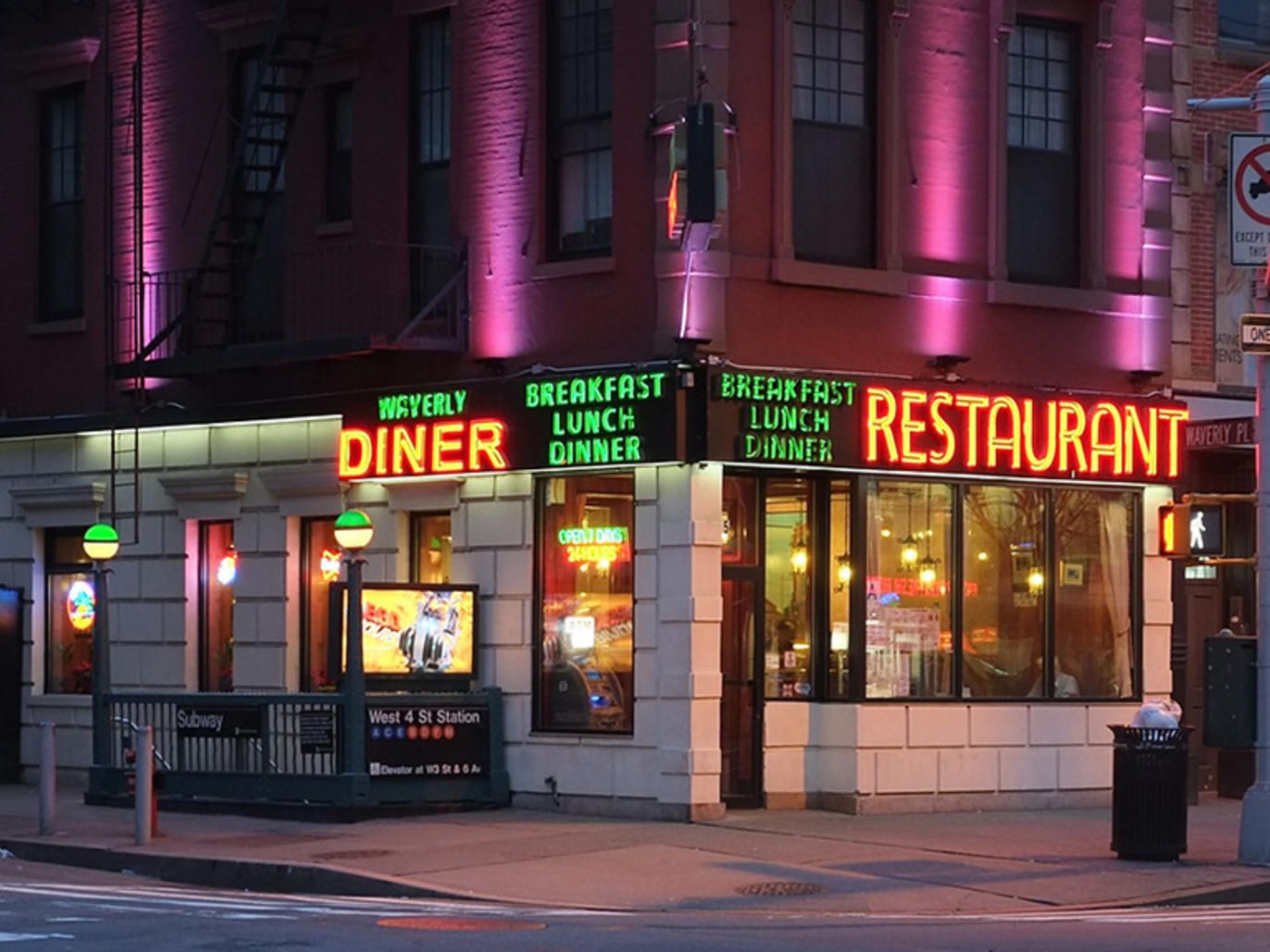 Late-night NYC restaurant street scene with warm dining room lights, people walking after shows, concerts, games, and a night out