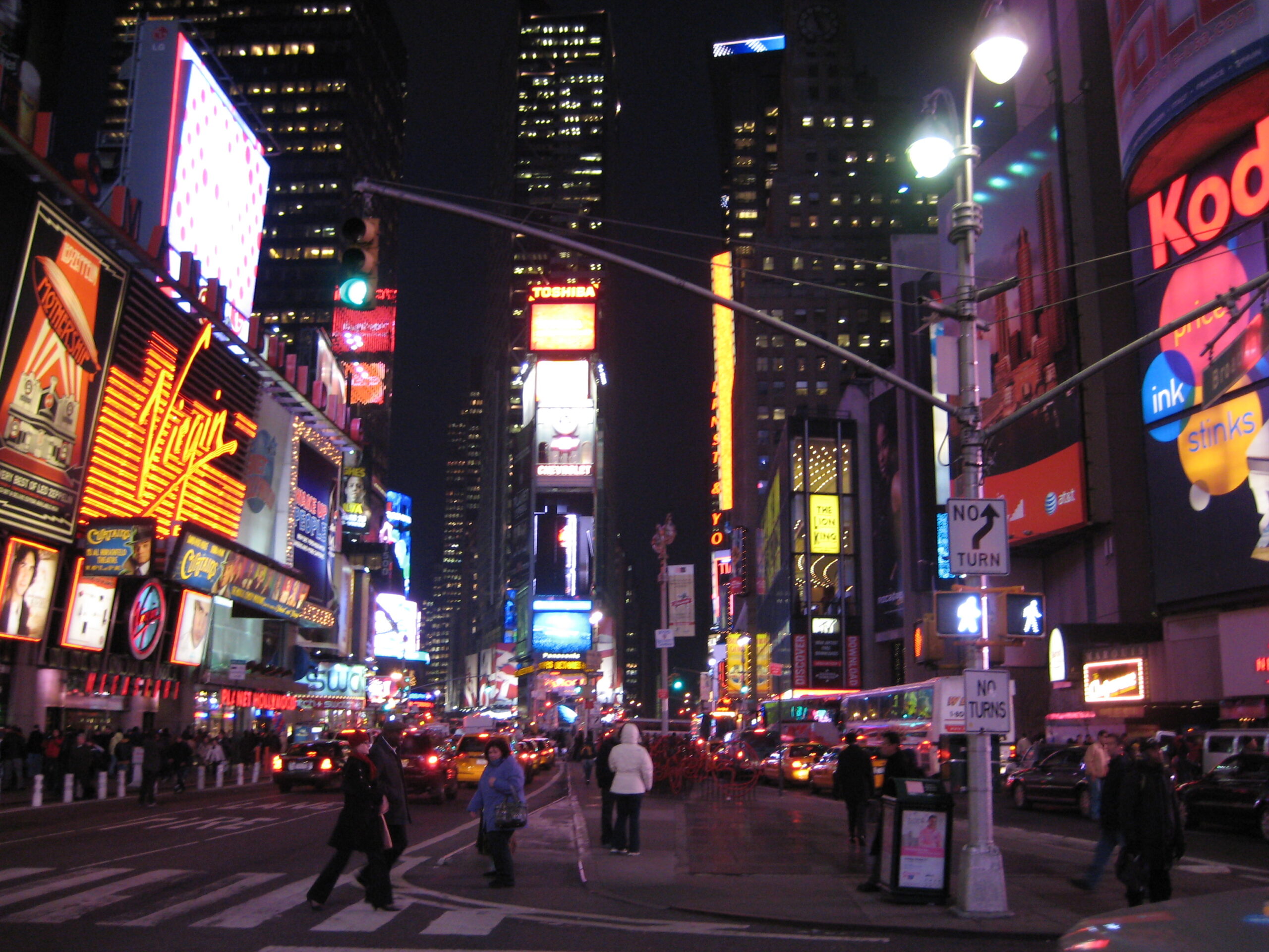 Yellow taxi in Times Square at night for comparing Uber, Lyft, and taxis after Broadway shows and NYC events