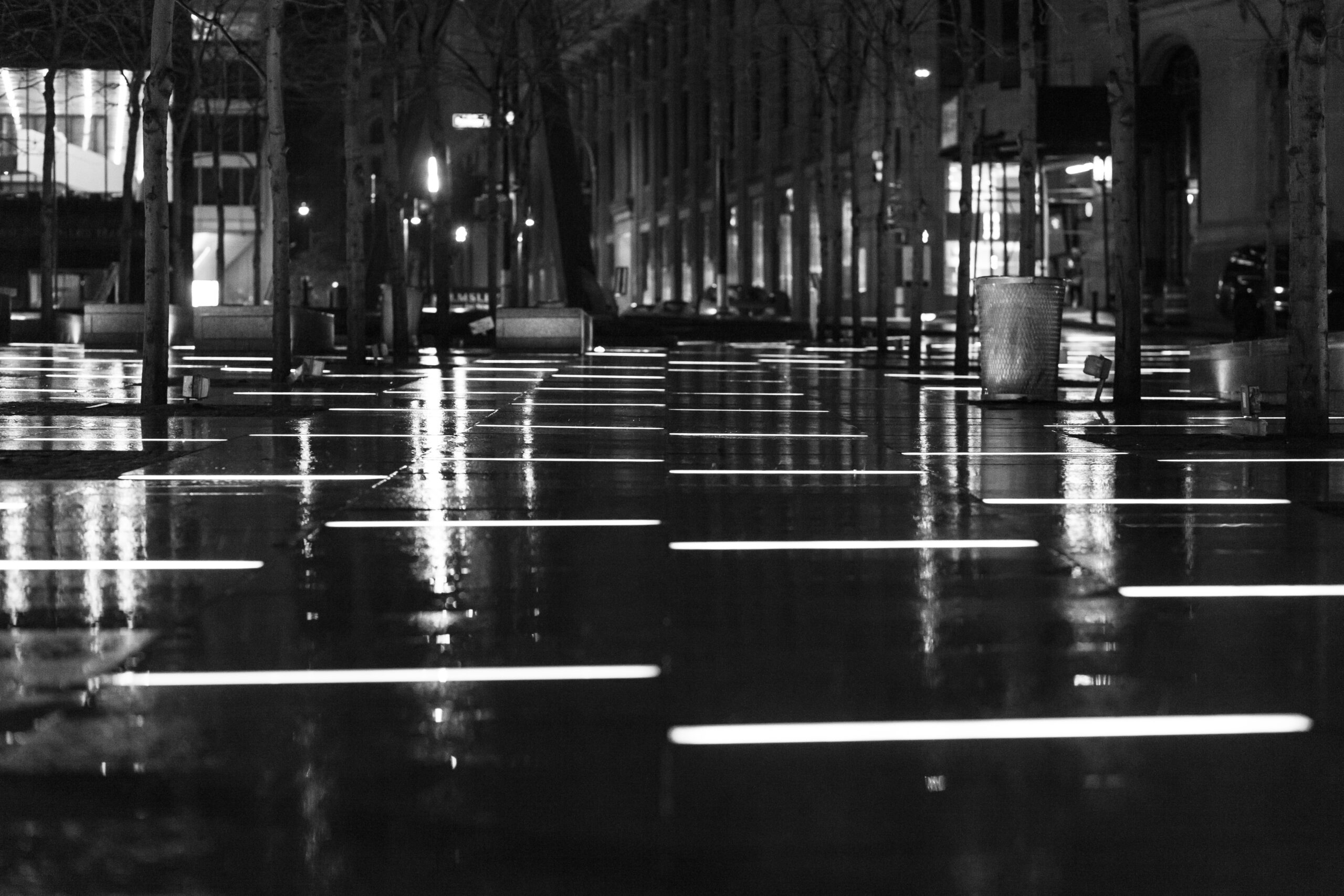 Rainy night street scene in Manhattan with wet pavement, city lights, and New York City atmosphere