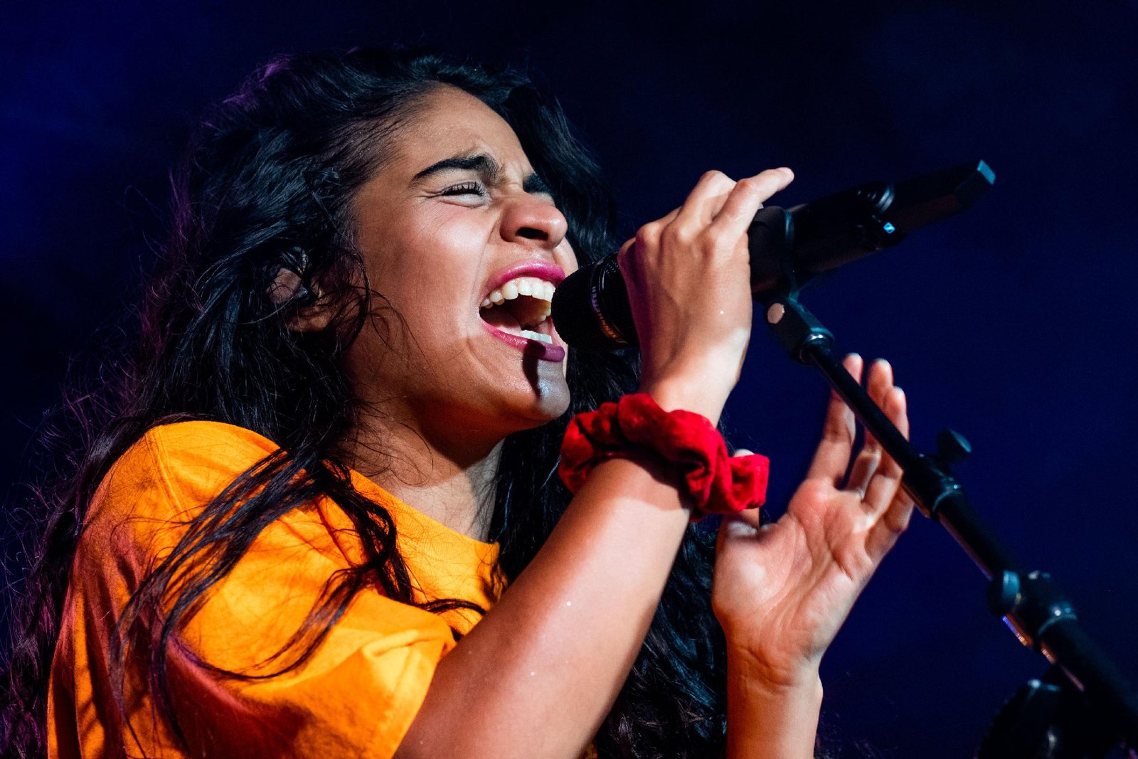 Jessie Reyez singing into a microphone during a live concert performance